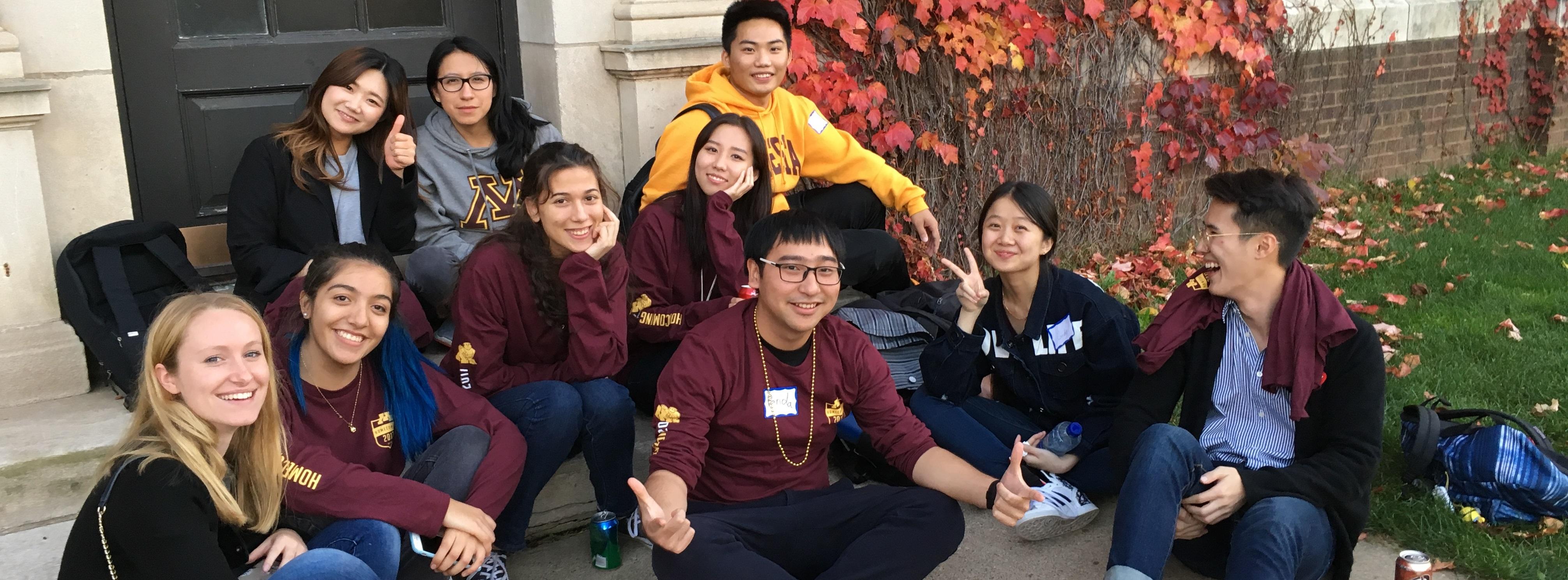 Students sitting on step outside at UMN Homecoming